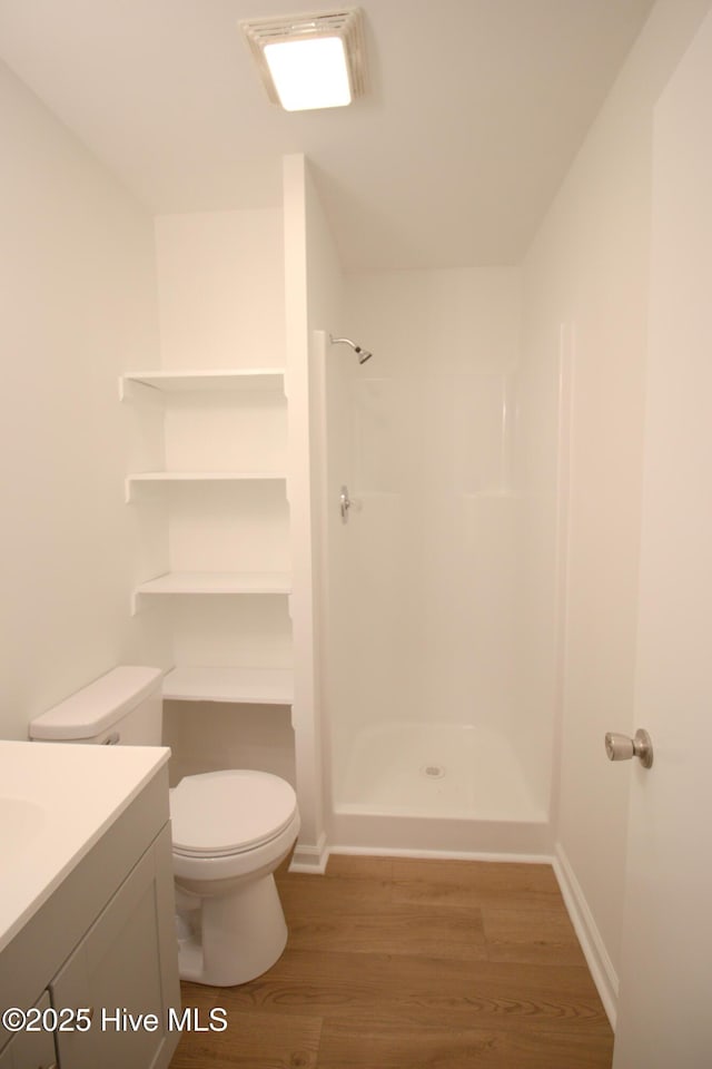 full bath featuring baseboards, toilet, wood finished floors, walk in shower, and vanity