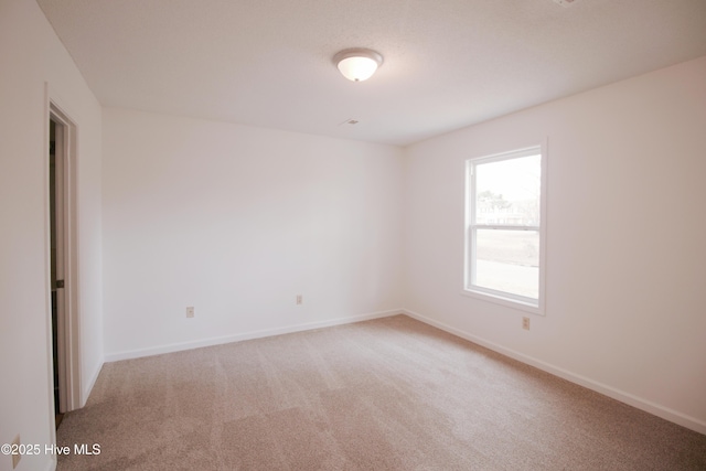 unfurnished room featuring carpet floors and baseboards