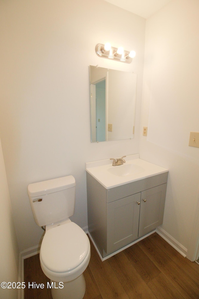 bathroom with baseboards, vanity, toilet, and wood finished floors