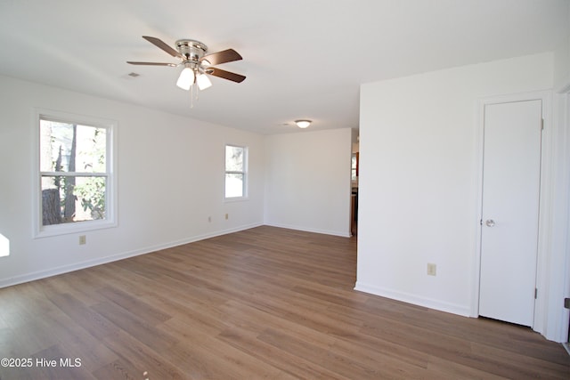 spare room with ceiling fan, wood finished floors, visible vents, and baseboards