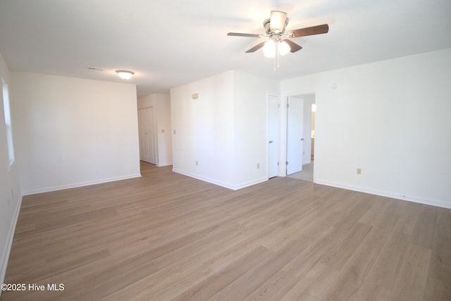 spare room featuring light wood finished floors, ceiling fan, and baseboards