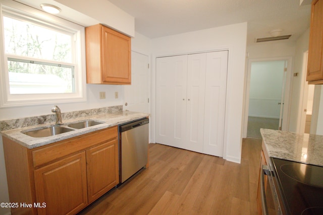 kitchen featuring light stone counters, visible vents, light wood-style flooring, stainless steel dishwasher, and a sink