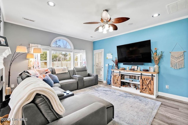 living room featuring ornamental molding, visible vents, light wood-style floors, and baseboards