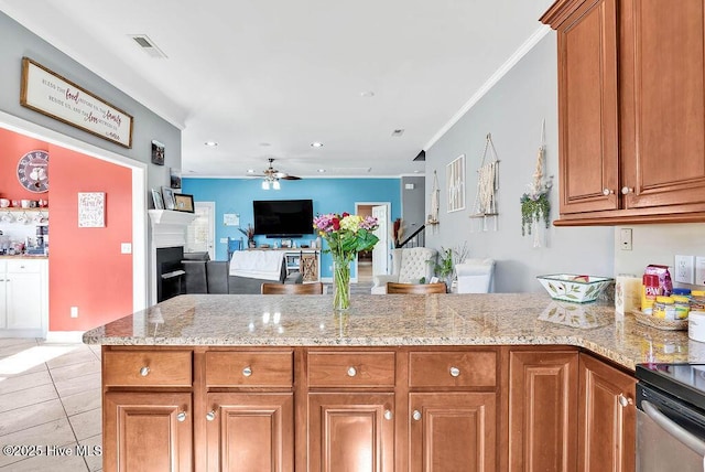 kitchen with open floor plan, light stone counters, brown cabinetry, and a fireplace