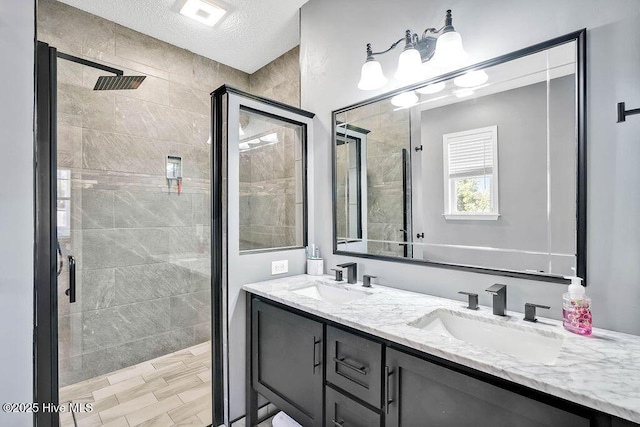 bathroom featuring double vanity, a textured ceiling, a sink, and tiled shower