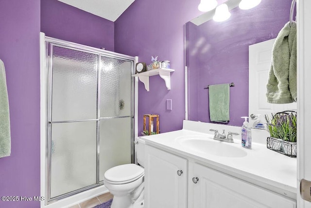 bathroom with toilet, tile patterned flooring, a shower stall, and vanity