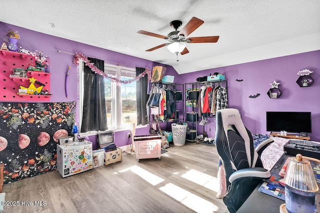 office space with a textured ceiling, ceiling fan, vaulted ceiling, and wood finished floors