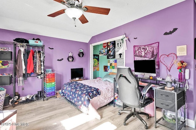 bedroom with light wood-style floors, lofted ceiling, and a ceiling fan