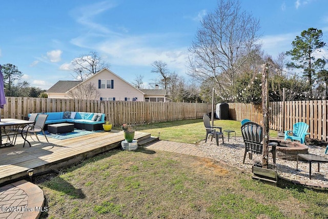 view of yard with a fenced backyard, a deck, and an outdoor living space with a fire pit