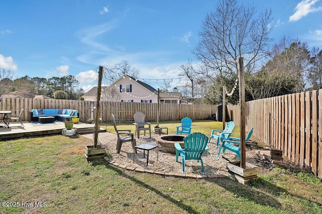 view of yard featuring a fenced backyard, a deck, and an outdoor living space with a fire pit