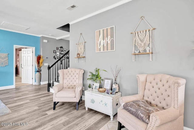 living area featuring visible vents, baseboards, stairs, ornamental molding, and light wood-type flooring