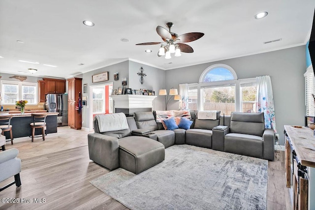 living area with visible vents, ceiling fan, ornamental molding, light wood-style floors, and recessed lighting