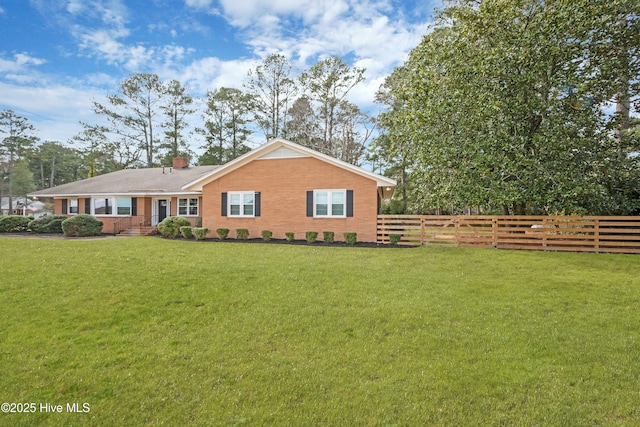 view of front facade with brick siding, a chimney, a front lawn, and fence