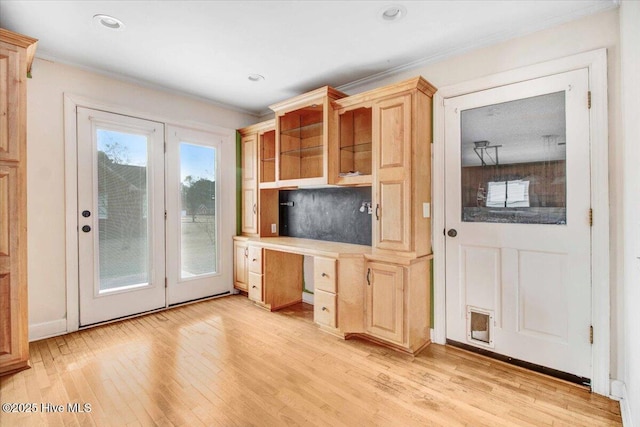 kitchen with ornamental molding, open shelves, built in desk, and light wood-style floors