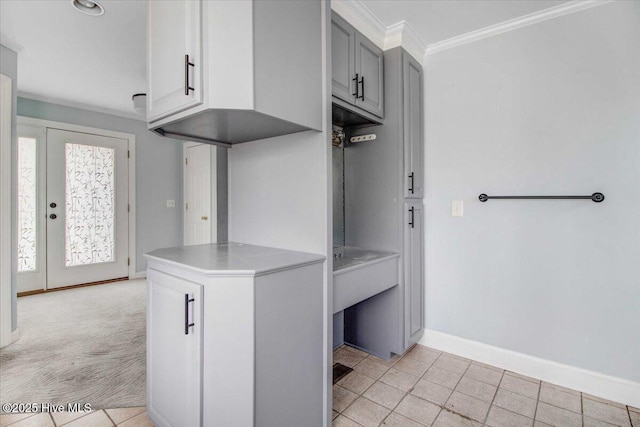 kitchen with light carpet, baseboards, ornamental molding, light countertops, and gray cabinetry