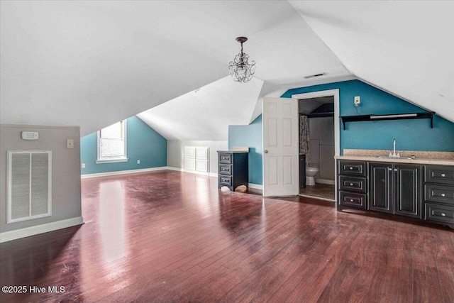 bonus room with indoor wet bar, dark wood finished floors, visible vents, and a sink