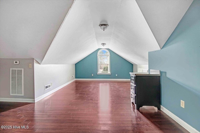 bonus room with wood-type flooring, visible vents, vaulted ceiling, and baseboards