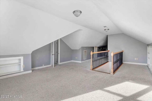 bonus room with lofted ceiling, carpet, built in shelves, and baseboards