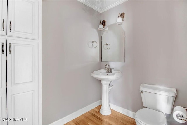 bathroom featuring baseboards, crown molding, toilet, and wood finished floors