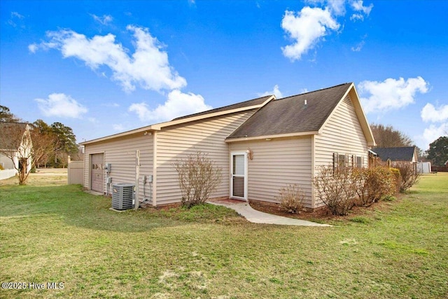 back of property with a shingled roof, a yard, and central air condition unit