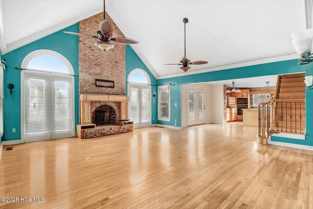 unfurnished living room featuring light wood finished floors, stairway, a fireplace, and crown molding