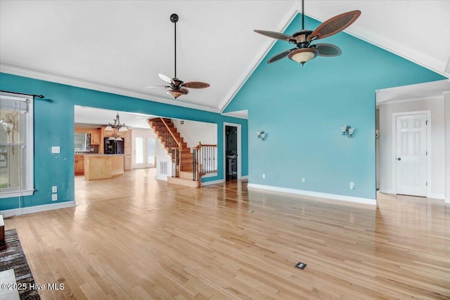 unfurnished living room featuring crown molding, light wood-style flooring, baseboards, and stairs