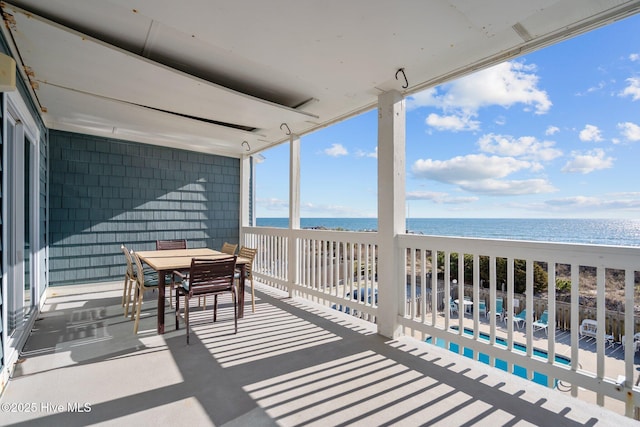 balcony with a water view, outdoor dining area, and a view of the beach