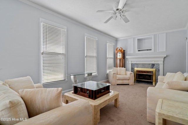 living area with a ceiling fan, baseboards, a fireplace, ornamental molding, and carpet flooring