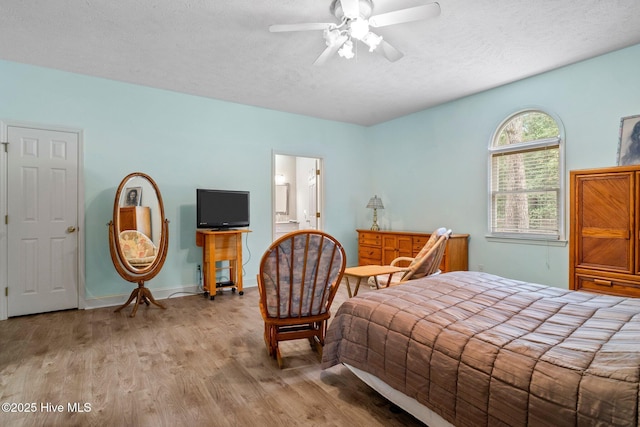 bedroom featuring ensuite bathroom, a textured ceiling, wood finished floors, baseboards, and ceiling fan