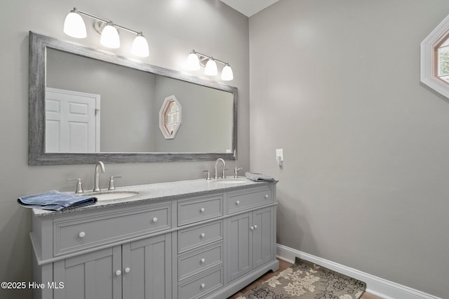 bathroom featuring double vanity, baseboards, and a sink