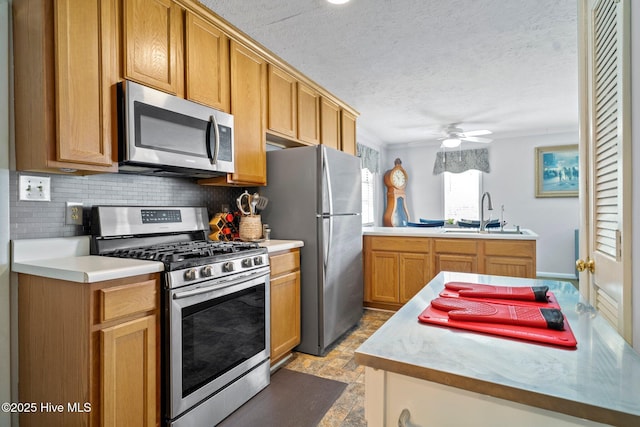 kitchen with a ceiling fan, a sink, stone finish flooring, backsplash, and stainless steel appliances