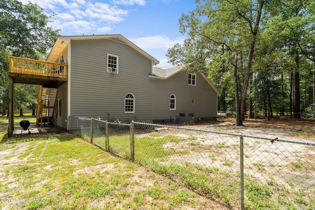 rear view of property with a deck, cooling unit, fence, and a yard