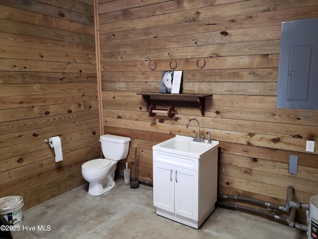 bathroom featuring concrete floors, wood walls, toilet, electric panel, and vanity