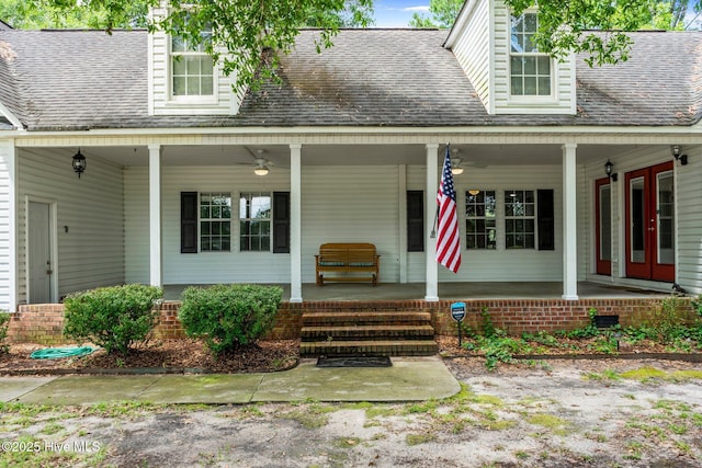 view of exterior entry featuring covered porch, a shingled roof, and a ceiling fan