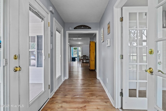 corridor featuring light wood-style floors and baseboards