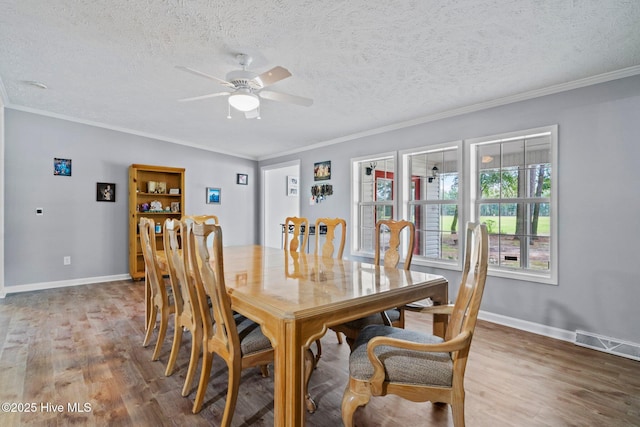 dining room featuring wood finished floors, crown molding, a ceiling fan, and visible vents