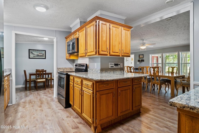 kitchen featuring a ceiling fan, light stone counters, light wood-style floors, and stainless steel appliances