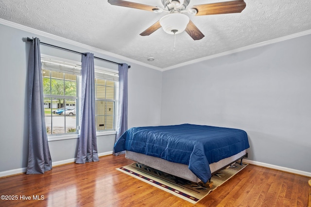 bedroom featuring baseboards, a textured ceiling, wood finished floors, and ornamental molding