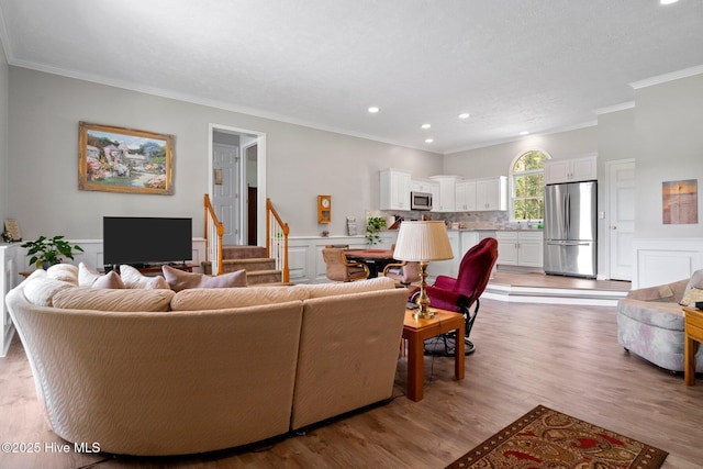 living room featuring crown molding, stairway, recessed lighting, wainscoting, and light wood-style floors