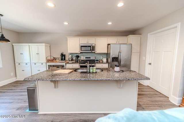 kitchen with light wood-type flooring, a breakfast bar area, stainless steel appliances, and a sink