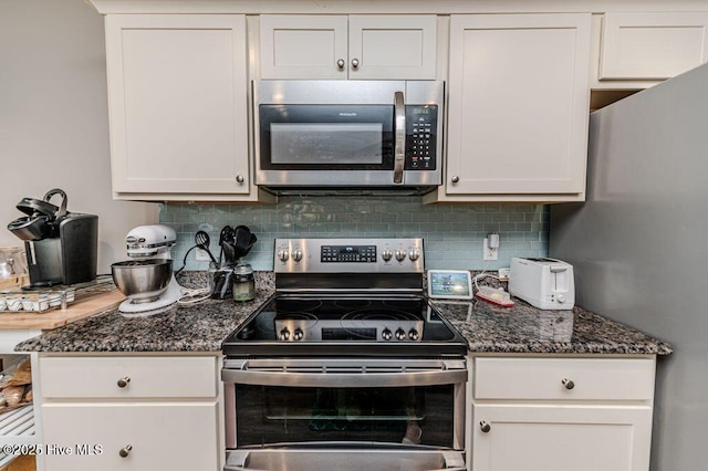 kitchen featuring white cabinets, dark stone counters, stainless steel appliances, and decorative backsplash