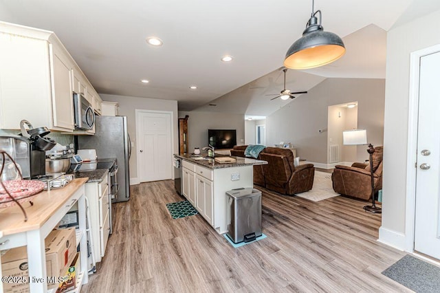 kitchen with white cabinets, stainless steel appliances, a sink, and open floor plan