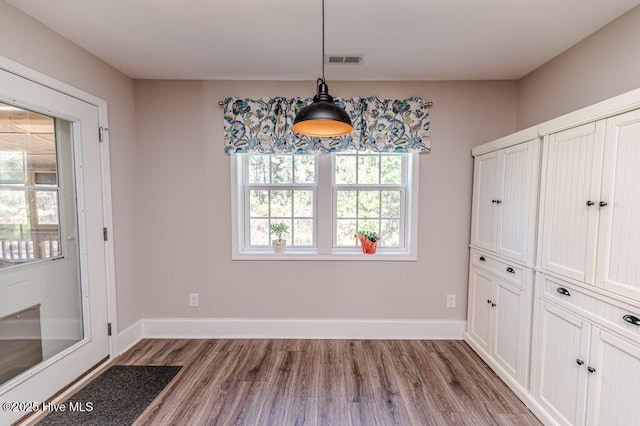 unfurnished dining area featuring wood finished floors, visible vents, and baseboards