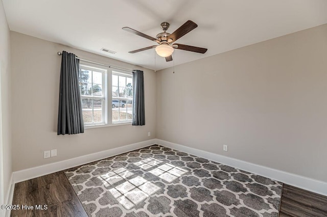 empty room featuring ceiling fan, wood finished floors, visible vents, and baseboards