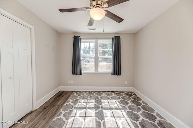 spare room with a ceiling fan, visible vents, baseboards, and wood finished floors