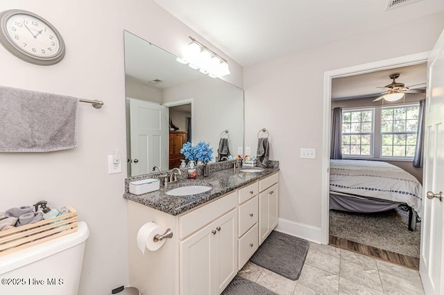 bathroom featuring double vanity, connected bathroom, baseboards, and a sink