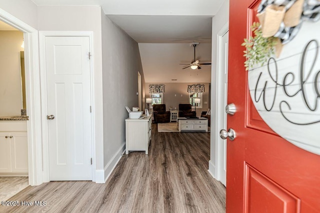 entryway with wood finished floors, a ceiling fan, and baseboards