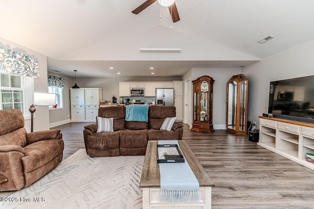 living area with lofted ceiling, visible vents, and light wood-style flooring