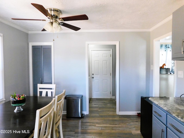 dining area featuring baseboards, a textured ceiling, dark wood finished floors, and crown molding