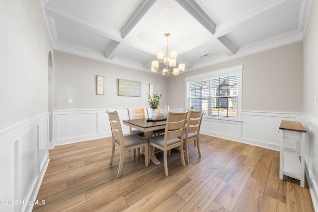 dining area featuring light wood-type flooring, a notable chandelier, coffered ceiling, and beamed ceiling